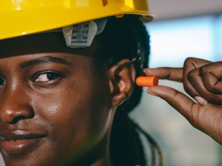 construction worker-hearing protection Female construction worker using earplugs as hearing protection.