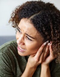 Woman in distress holds hand to her ear.