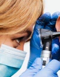 Doctor performing an ear exam on man with tinnitus.