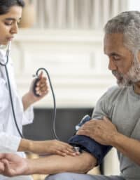 Doctor checking a man's blood pressure.
