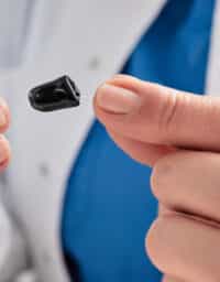 Audiologist holding a small hearing aid and battery