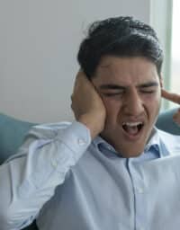 Man covering his ears to block out tinnitus.