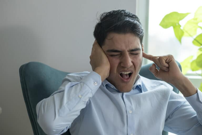 Man covering his ears to block out tinnitus.