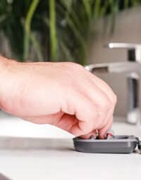Close up of a hand grabbing hearing aids from their case.