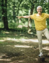 Woman balancing on a log in the woods.