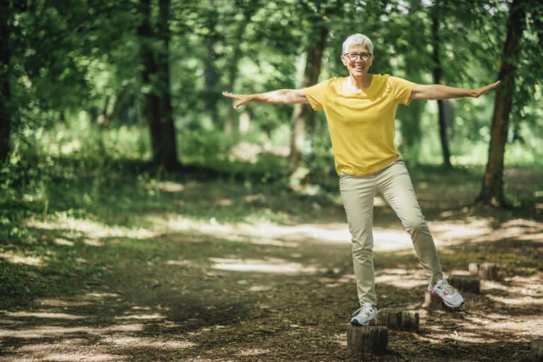Balancing Exercise Outdoors Woman balancing on a log in the woods.